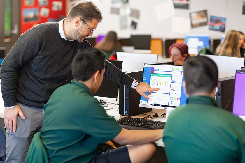 teacher working with students in the classroom on computers using banqer high
