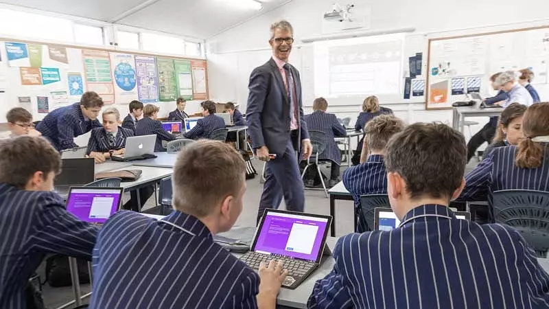 teacher at st andrews college walking his classroom surrounded by students using banqer